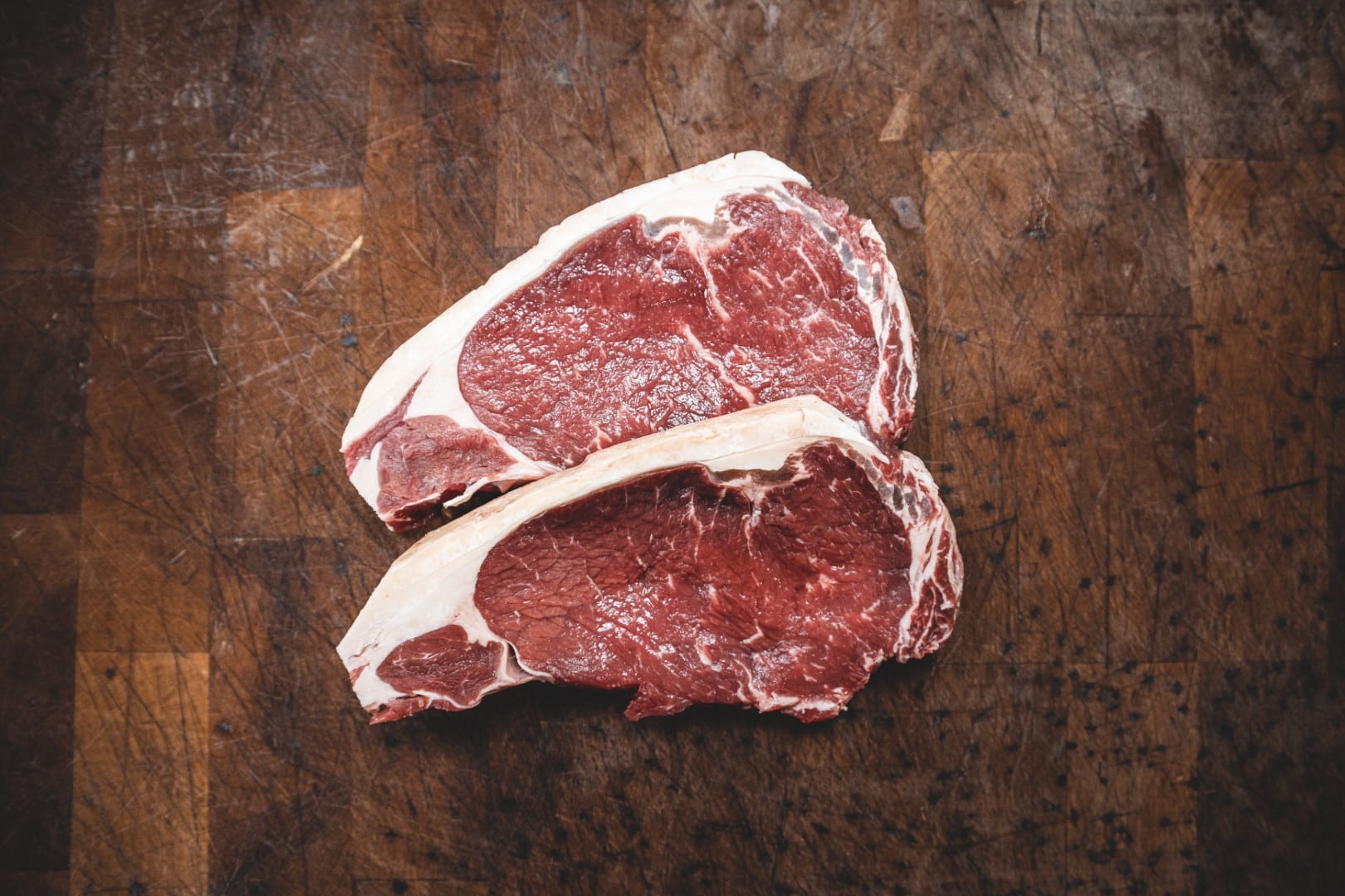two raw steaks on cutting board