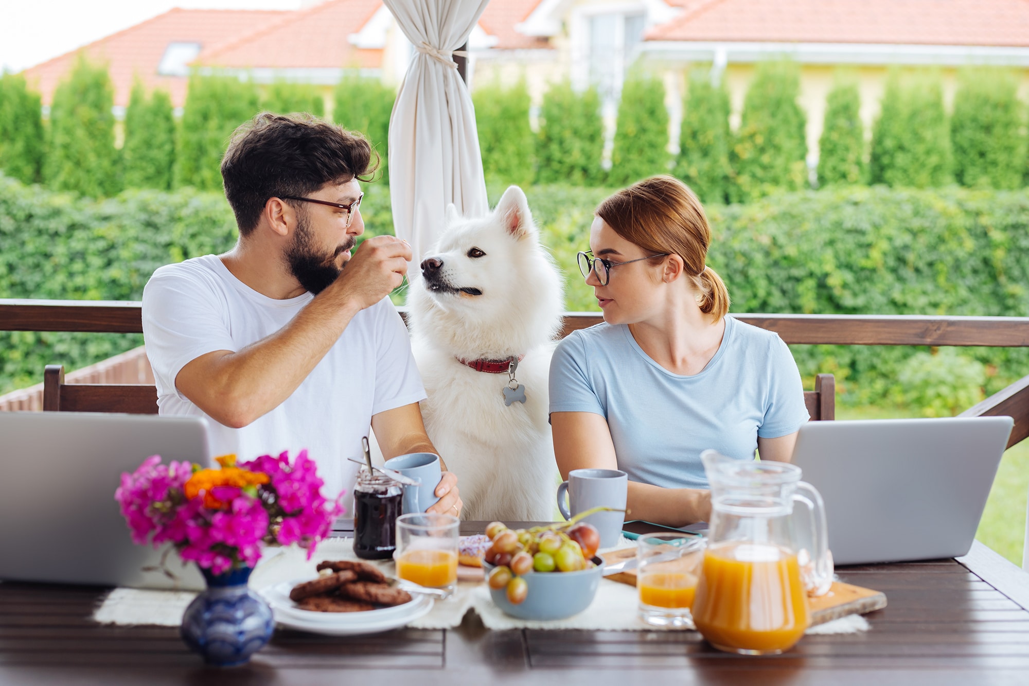 A couple eats breakfast with their dog.
