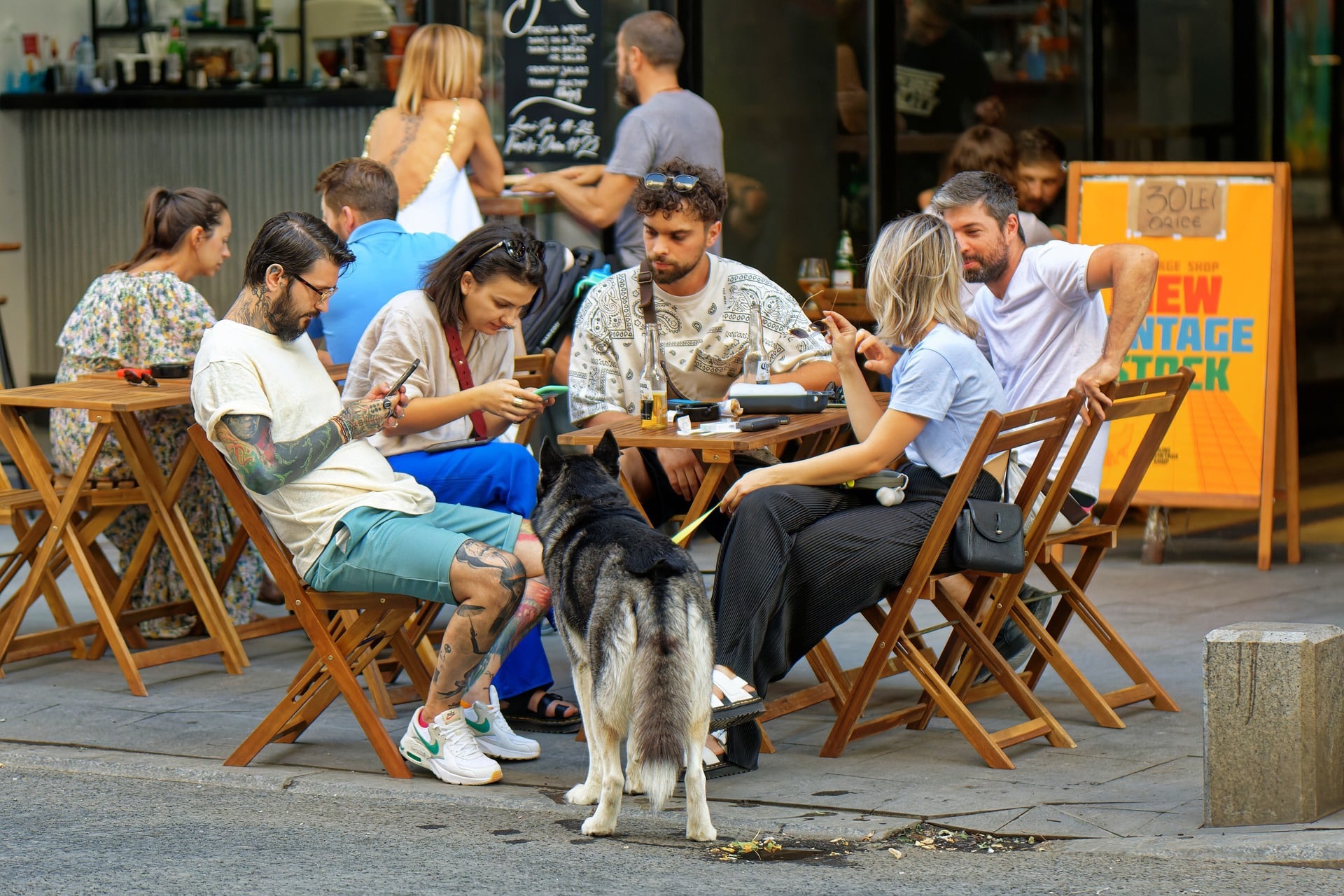 A group of people sit at a dog-friendly restaurant with their dog by the table.